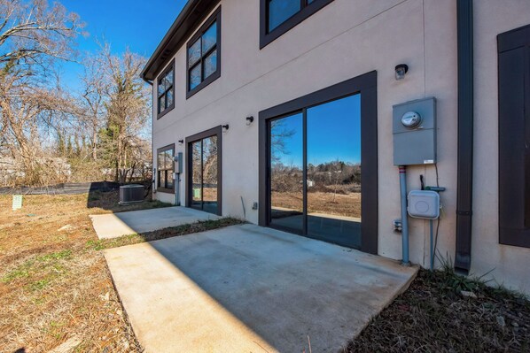 A modern two-story building with large glass doors and windows, a concrete pathway, and outdoor electrical boxes.