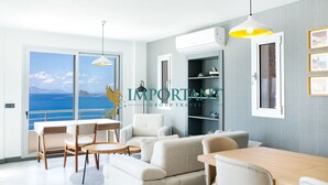 Una sala moderna con vista al mar, un comedor y una estantería.
