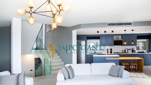 Una sala de estar moderna con un sofá, una escalera y una zona de cocina.
