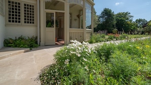 A two-story house with a balcony, a garden with various plants and flowers, and a door leading to the interior. - Windy Ridge - sleeps 16 guests  in 6 bedrooms (Bembridge)