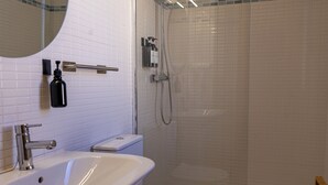 A bathroom with a white sink, a toilet, a shower with a glass door, and a mirror above the sink.