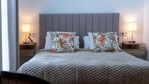 A neatly made bed with a grey headboard, two nightstands with lamps, and floral-patterned pillows.