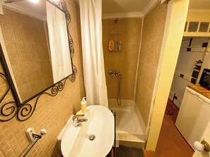 Ein Badezimmer mit einem weißen Waschbecken, einem Spiegel, einer Dusche und einer Toilette.