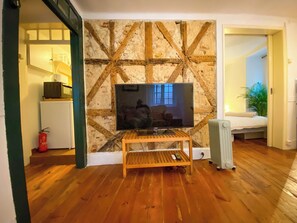 Ein Wohnzimmer mit Fernseher auf Holzständer, Kamin und Pflanze.