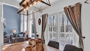A dining area with a wooden table, birch-patterned stools, and a modern chandelier.