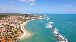 Vista aérea de un pueblo costero con playa, casas y aguas azules cristalinas.