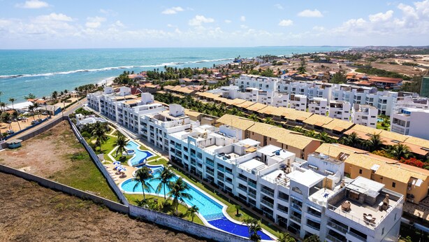 Un resort con varias edificaciones, una piscina y vista al océano.