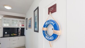 Un pasillo con una zona de cocina, un flotador con el texto "WELCOME ABOARD" y un letrero que indica "C31".