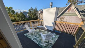Une terrasse sur le toit avec deux fauteuils Adirondack, une petite table ronde et un tapis à motifs.