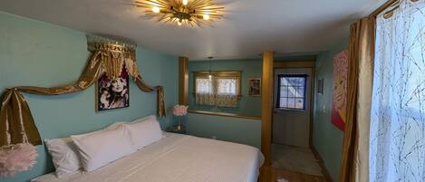 Un dormitorio con cama, candelabro, puerta y ventana.