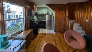 Une cuisine compacte aux murs en bois, dotée d’un réfrigérateur en acier inoxydable et d’une fenêtre donnant sur un balcon.