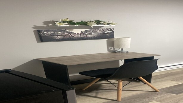 Ein moderner Schreibtisch mit Stuhl, Lampe und einem gerahmten Bild an der Wand.