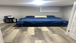 Ein Schlafzimmer mit Bett, Nachttisch, Fenster und Tür.