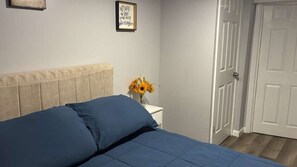 A bedroom with a bed, a nightstand, a vase with sunflowers, and a door.