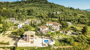 Zona residencial com casas numa encosta, piscina e uma igreja no topo da colina.