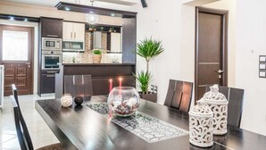 Cozinha moderna com armários escuros, uma ilha central com uma tigela de vidro e velas, e potes decorativos na ilha.