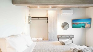 Een moderne hotelkamer met een groot bed, een nachtkastje met handdoeken, een wandtelevisie en een airconditioning.