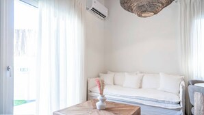 Een moderne woonkamer met een witte bank, een houten salontafel met een vaas, en een hanglamp.