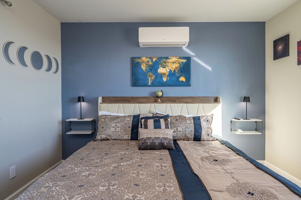 Un dormitorio con cama, un mapa mundial en la pared y un ventilador de techo.