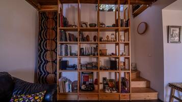 A cozy living room with a wooden bookshelf filled with books, decorative items, and a small table.