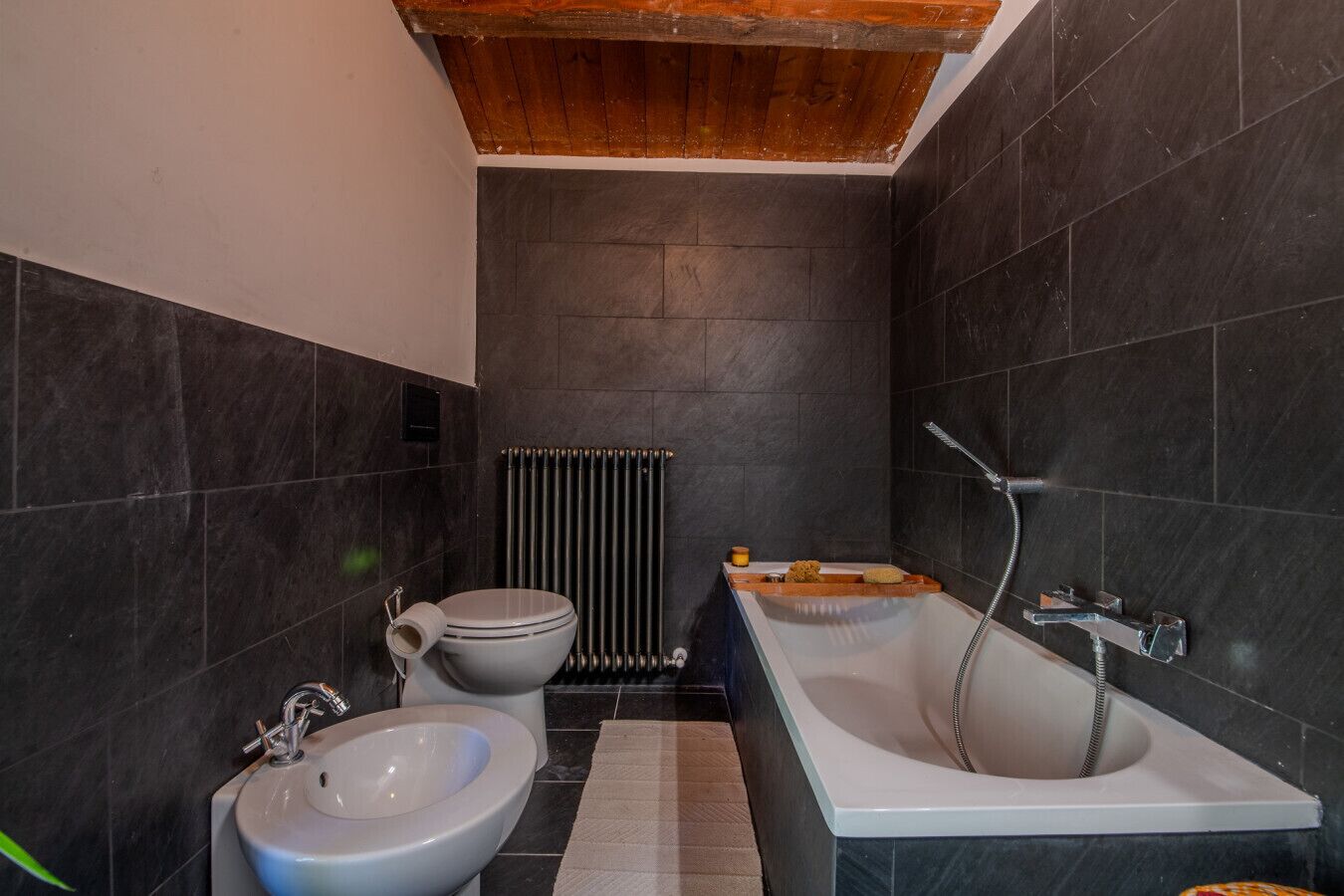 A modern bathroom with a toilet, bidet, and bathtub.