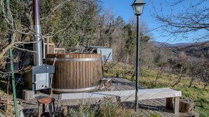 Un jacuzzi rústico al aire libre con una terraza de madera, un calentador de metal y una farola.