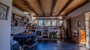Una cocina rústica con techo de madera, un comedor con una mesa redonda y sillas, y vistas al exterior por la ventana.
