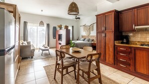 Une cuisine spacieuse avec des meubles en bois, un coin repas avec une table et des chaises, et un salon avec un canapé et un téléviseur.