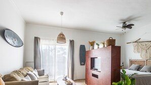 Un salon moderne avec un canapé, une table basse, un téléviseur et un lit doté d’une tête de lit.