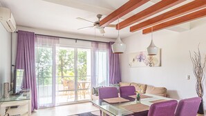 A modern living room with a glass dining table, purple chairs, a sofa, and a ceiling fan. - Infiniti Blu, Family Suite, Private Beach! (Sosúa)