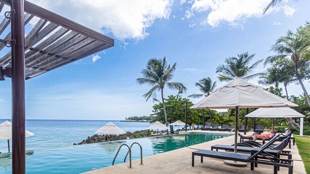 A pool area with lounge chairs and umbrellas, overlooking the ocean. - Infiniti Blu, Family Suite, Private Beach! (Sosúa)