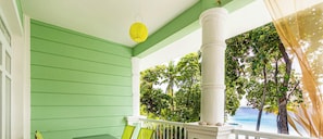 A porch with a view of the ocean, green walls, and a hanging lantern. - Sosúa, Beach Front With Ocean Views, (Sosúa)