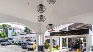 L’entrée de l’hôtel Apartha Monte Vista, avec un espace extérieur couvert, des colonnes et des lampes suspendues.