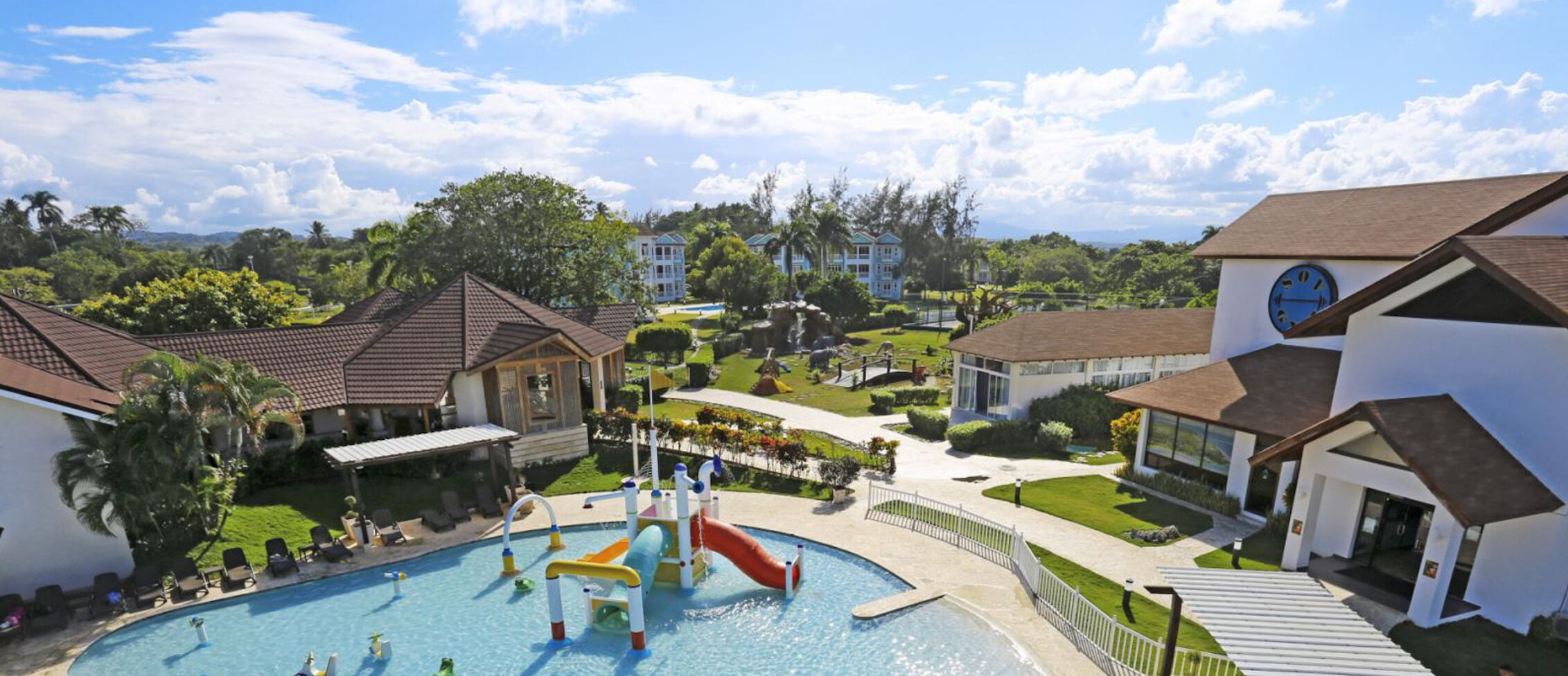 A resort with a swimming pool, a water slide, and a clock tower.