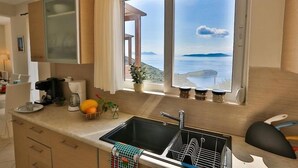 Eine Küche mit einem großen Fenster, einem Spülbecken und einer Arbeitsplatte mit verschiedenen Gegenständen.
