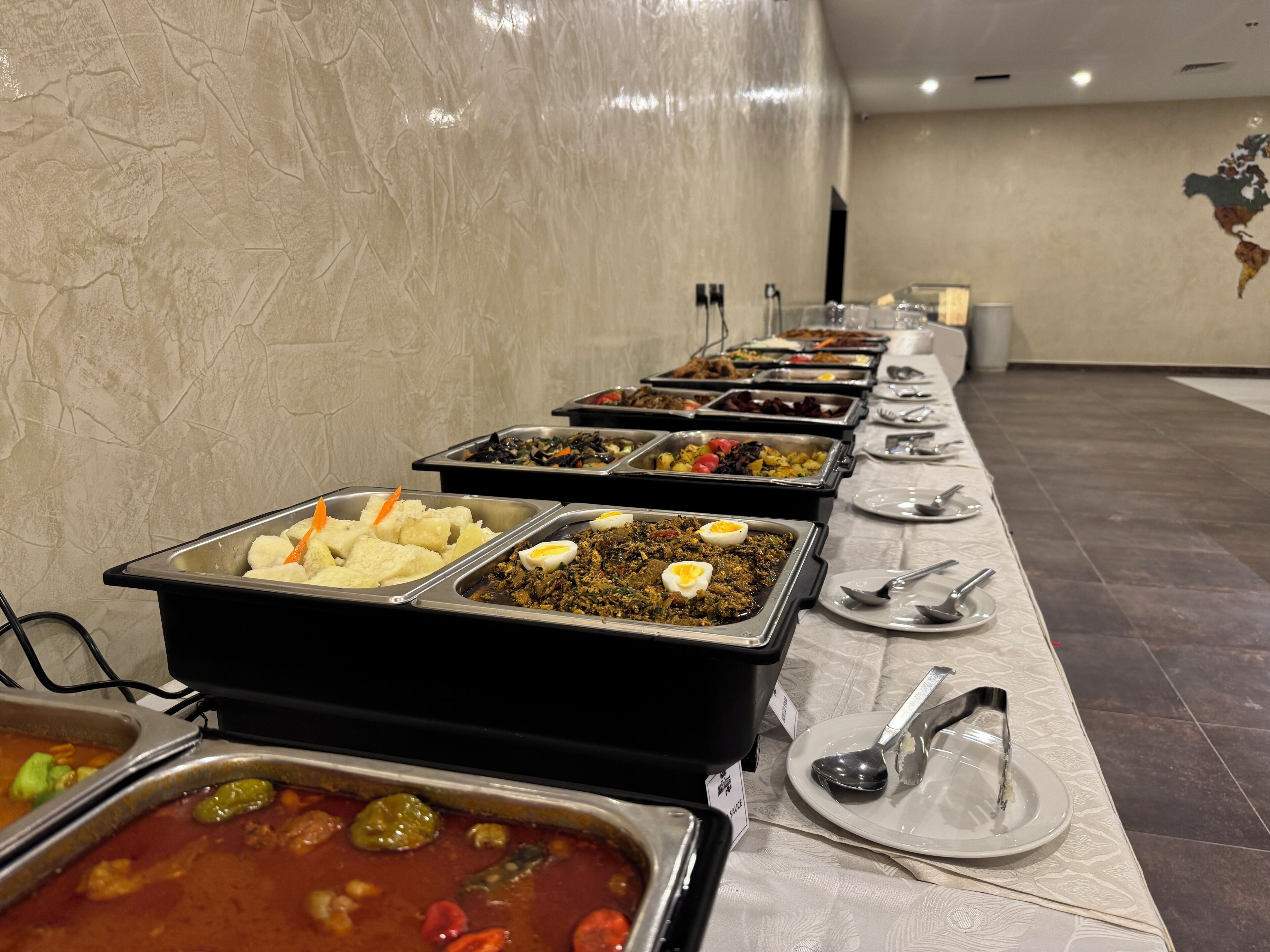 A buffet line with various food items, including a dish with a boiled egg, a salad, and a red sauce.