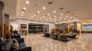 A spacious lobby with seating areas, a reception desk, and a large screen. - The Palms by Eagles Airport City (Accra)