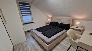 Een slaapkamer met een bed, nachtkastjes, een stoel en een bureau.