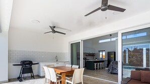 Et moderne køkken med spiseplads, grill og en skydedør, der fører ud til en balkon.