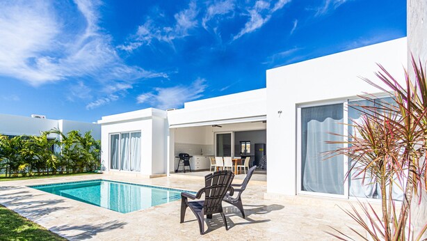 Et moderne hus med swimmingpool, havemøbler og udsigt til himlen.