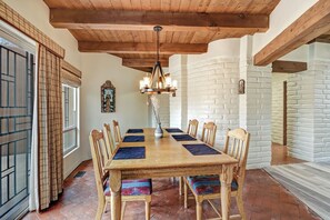A dining area with a wooden table, chairs, and a hanging light fixture. - Spacious Adobe home near Old Town in Albuquerque, New Mexico. (Albuquerque)