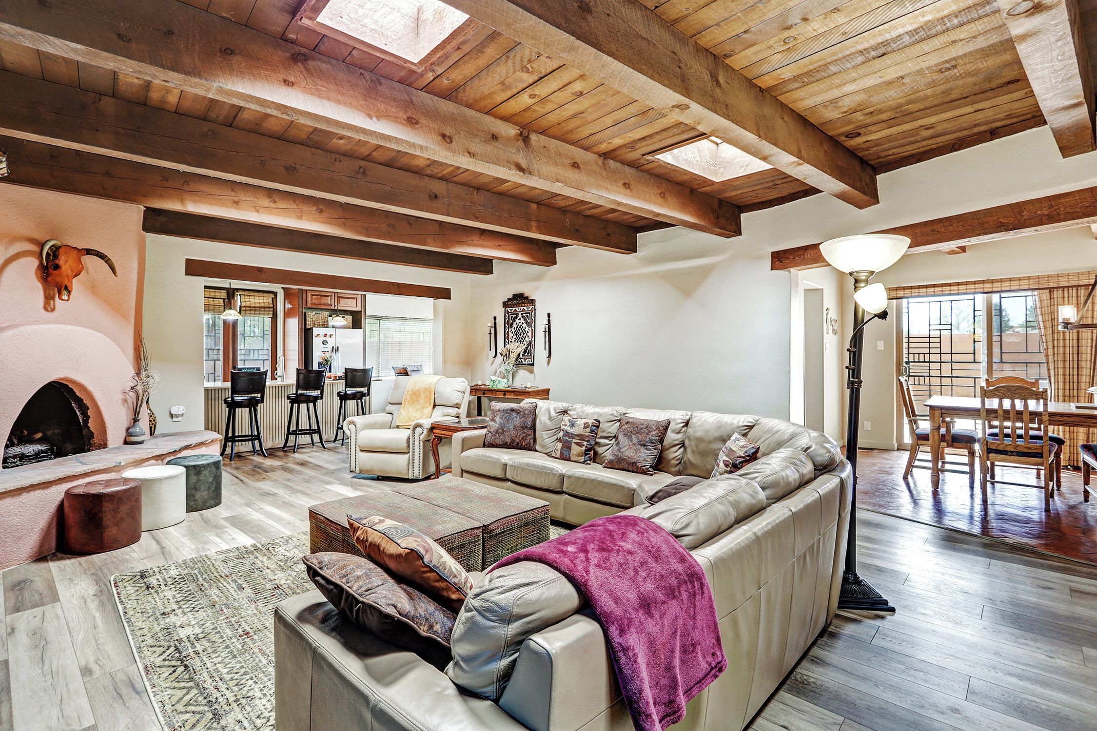 A spacious living room with a large sectional sofa, a fireplace, and a dining area with a table and chairs.