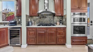 A kitchen with wooden cabinets, a stainless steel range hood, a built-in oven, and a dishwasher. - Game Lovers` Retreat: 4000 sqft of Fun (El Dorado Hills)
