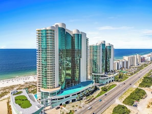 A high-rise hotel with multiple floors, a curved structure, and a view of the ocean.