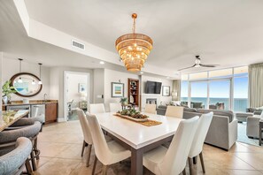 Un salon moderne avec un coin repas, un grand lustre et une vue sur l’océan.