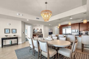 A spacious kitchen with modern appliances, a dining area with a large round table and chairs, and a chandelier. - Beach Luxury ~ Turquoise C1805 Balcony HotTub & TV (Orange Beach)
