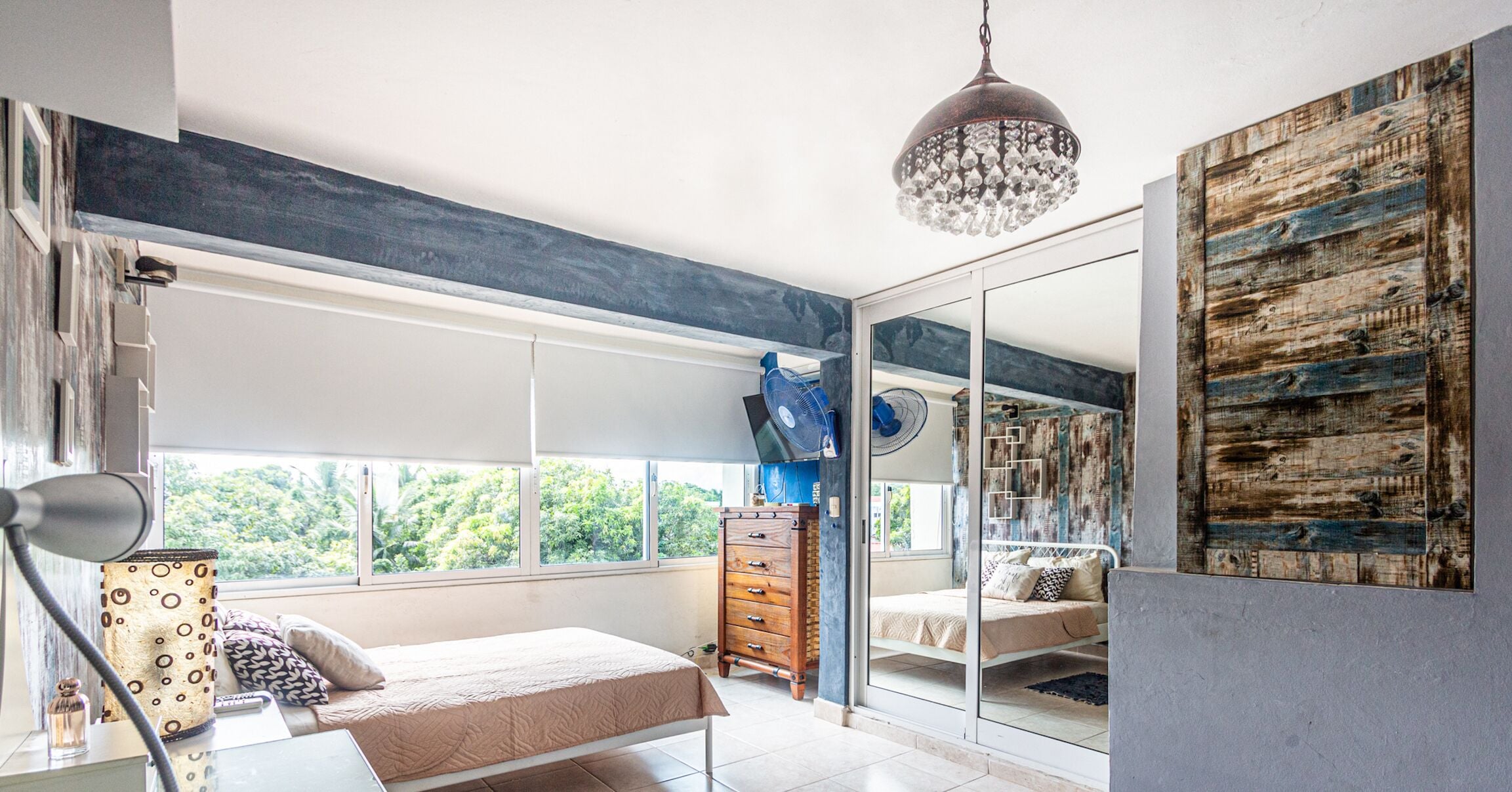 Une chambre à coucher avec un lit, une commode et une grande fenêtre.
