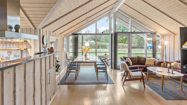 A spacious, well-lit room with a high ceiling, large windows, a dining area, and a cozy seating area. - Awesome home in Rødby with sauna (Rødby)