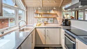 A modern kitchen with wooden cabinets, a granite countertop, and a large window providing natural light. - Awesome home in Rødby with sauna (Rødby)