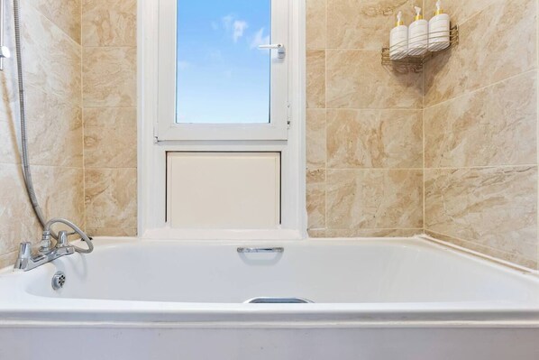 Un baño con bañera, ducha y ventana.